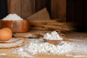 White wheat flour in a wooden spoon with barley ears Rice grains and eggs natural agricultural food on a dark wooden background