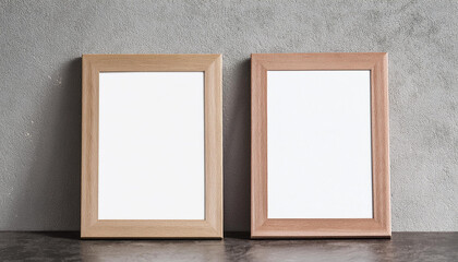 Fototapeta premium Two empty white picture frames with wooden frame leaning on cement wall. Blank poster. Mock-up
