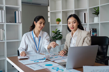 Obraz premium Professional Business Meeting with Two Women Analyzing Data on a Laptop in a Modern Office Setting