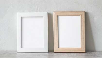Two empty white picture frames with wooden frame leaning on cement wall. Blank poster. Mock-up