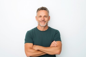 Happy middle aged man isolated on white studio background. Confident mature mid adult handsome male model wearing t-shirt looking at camera with arms crossed.