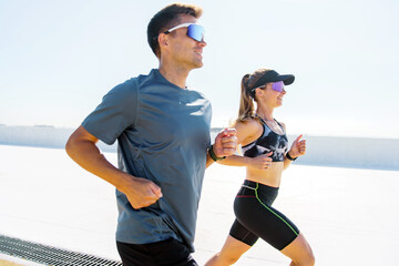 Two Runners Enjoying a Bright Sunny Day While Exercising Along a Waterfront Promenade in the Early...