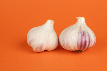 Fresh Organic Garlic Bulbs on Vibrant Orange Background for Modern Kitchen Decor
