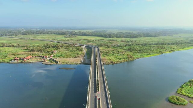 Aerial view of Kretek II bridge over Opak River with green plantation and blue sky horizon on the background. Yogyakarta, Indonesia.