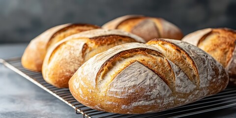 Naklejka premium Freshly baked bread loaves cooling on a wire rack, showcasing a golden crust and artisanal design.