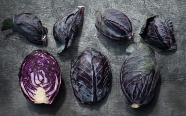 Close-up of fresh small and large heads of red cabbage. A head of cabbage is cut open. The...