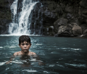 Fototapeta premium Young Boy Swimming in a Serene Waterfall Pool in a Tropical Jungle