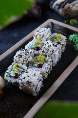 Sushi or rolls with smoked chicken, sesame and pineapple on a blackboard. Japanese cuisine. Vertical photo.