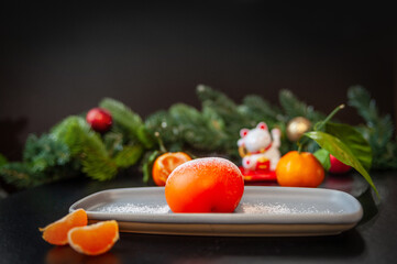 Plate with delicious mochi and tangerine on a dark Christmas background.