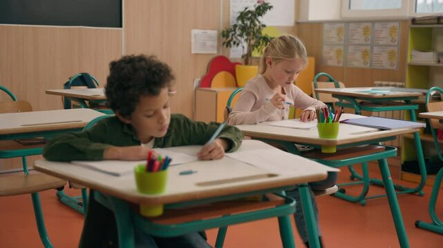 Elementary primary education studying in school multiracial pupils multiethnic children diversity kids African American son boy Caucasian girl daughter in classroom writing test exam write study learn