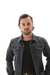 Headshot of bearded handsome man wearing denim jacket and looking at the camera. Vertical.