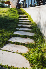 There is a beautifully designed set of concrete steps that gracefully lead up a picturesque grassy hill, inviting visitors to explore the natural beauty and enjoy the serene surroundings