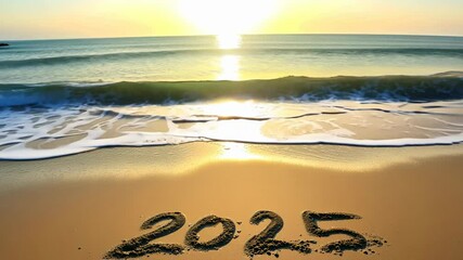 2025 written in the sand on a beach with waves gently rolling in at sunset, marking the new year.