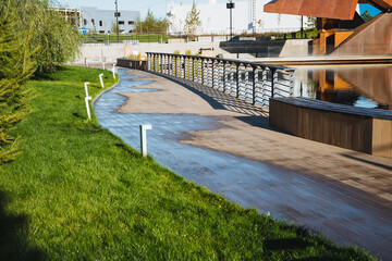 Fototapeta premium A concrete walkway surrounded by grass and trees in a park