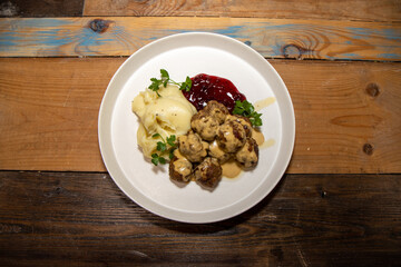 A delicious plate of Swedish meatballs with mash potatoes and lingonberry sauce on a white plate...