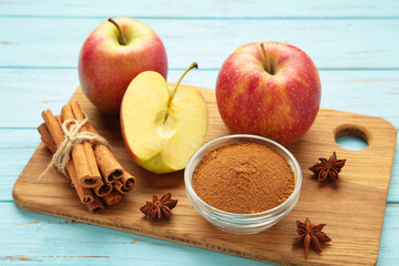 Red apple, apple slice, cinnamon sticks and star anise on blue wooden background.