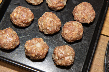 Raw uncooked beef meat balls on a baking trey ready to be put in the oven to cook