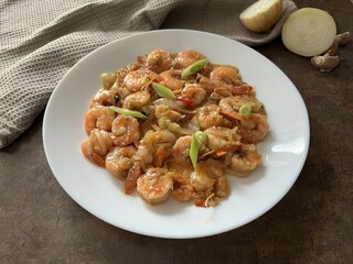 Stir-fried prawns with chili, green onion on a white plate on a rustic table. Asian style food. Perfect photo for cooking recipe, cooking book and creative design