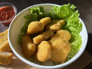 Chicken nuggets with green lettuce on white bowl. Fast food, unhealthy food