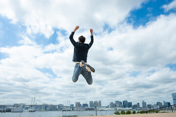 青空に向かって飛び跳ねる男性