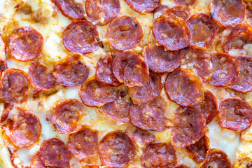 Close-up of sliced pizza with melted cheese triangles on a textured white background. Flat lay food photography