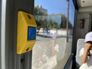 Yellow stop button on a bus window with blurred people in the background