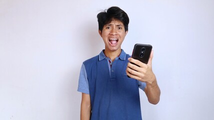 Asian young man surprised and strange gesture holding smartphone