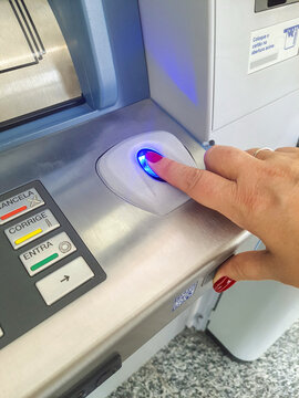 Fingerprint reader on ATM, female finger with red painted nail.
