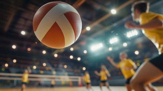 A volleyball in mid-air during a game with players in yellow jerseys in the background.