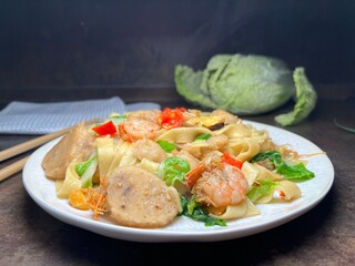 Spicy fried noodle with shrimp, chicken meat ball and vegetables. Thai style food.