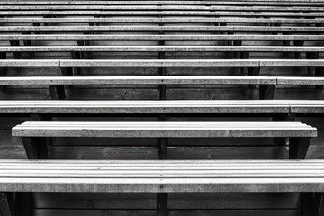 Rows of empty wooden bleachers in black and white, emphasizing minimalism and space.