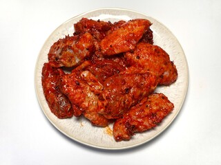 Marinated spicy chicken wings on a plate on a white background, isolated. Top view. Copy space. Semifinished. Fast cooking. Raw marinated chicken meat.
