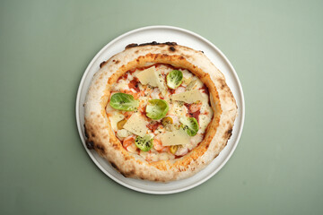 Pizza with shrimp, cheese and herbs on a white plate