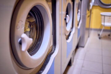 ф      young plus size  woman loads clothes into a washing machine in a laundry room in the...
