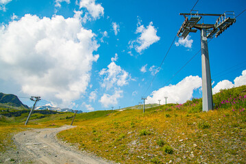 Trellis for chairlift with wires on a meadow during summer. Blue sky with white clouds on the...