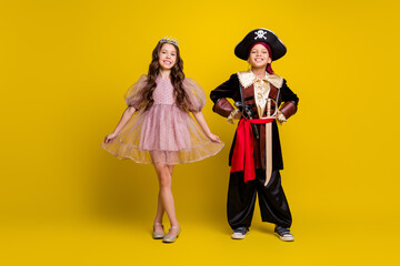Portrait of two small kids posing halloween pirate princess costume isolated on yellow color background