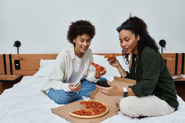 Two women share laughs and pizza in their cozy hotel room, capturing moments of love and adventure.