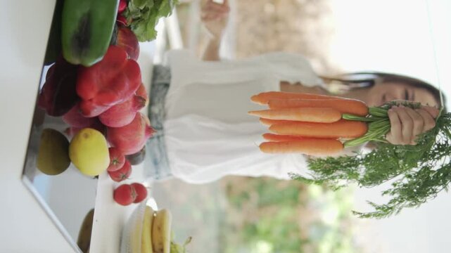 A female nutritionist holds out a bunch of fresh carrots with bata to the camera.