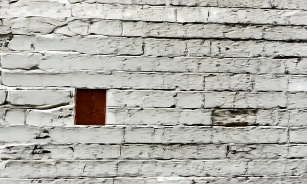 A textured white brick wall with assorted paint coverage, showcasing a rustic and varied appearance that adds character to architectural or interior design settings
