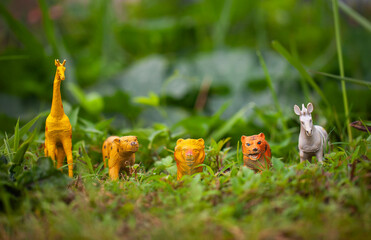 A collection of wild animal figurines, plastic toy miniatures in the natural environment. Tiger, Leopard, Lion, Zebra, Rhino, Bear, Giraffe.