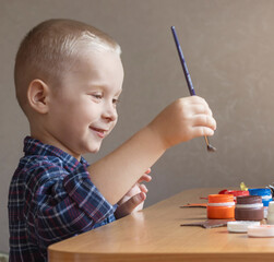 portrait of a boy painting with colored paints.  little child playing with paints