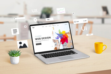 Fototapeta premium Laptop on a workspace displaying a web design studio webpage, with graphic web modules and elements floating around, illustrating the concept of dynamic website creation and design integration