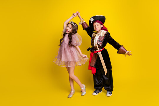 Full body portrait of two small kids halloween pirate princess costume dancing isolated on yellow color background