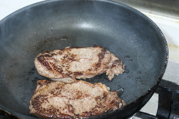 close up of homemade frying cooking two pieces of beef steak meat on a pan