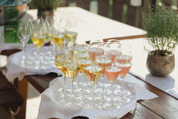 An elegant display of wine glasses filled with white and rosé wine, arranged on a white cloth atop a rustic wooden table.