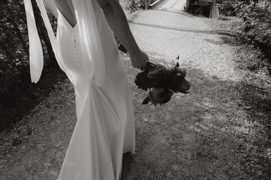 R&uuml;cken von Braut in wei&szlig;em Kleid mit Blumenstrau&szlig; bei Hochzeitsreportage drau&szlig;en