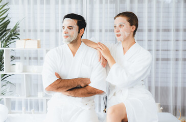 Fototapeta premium Serene modern daylight ambiance of spa salon, couple customer indulges in rejuvenating with facial skincare mask. Facial skin treatment and beauty cosmetology procedure for face. Quiescent