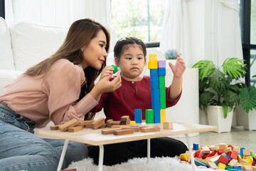 Cherry young mother plays colorful toy block with her Down syndrome daughter,  colorful wooden toys can increase skills and learning to increase the development, special education, Knowing slowly