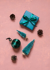 Christmas celebration concept composition with gift box, fir trees and ball on pink background