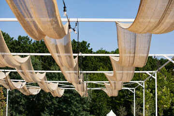 Fabric canopies anchored to steel structures for shading, white canvas stretched above terrace. Wedding or special events venue